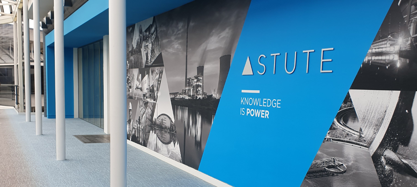 An image of four of energy recruitment agency Astute's team holding Young Lives vs Cancer signs, they are stood in front of balloons in the shape of the number 10000